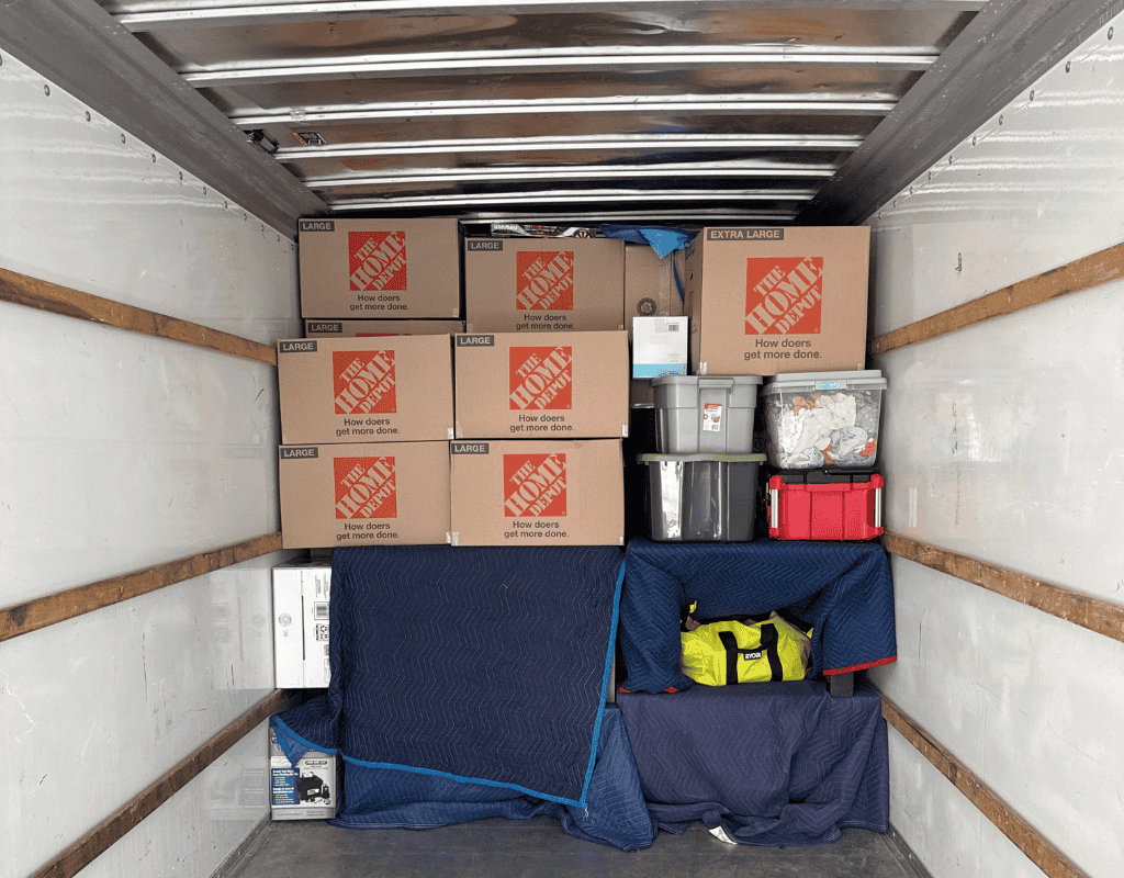 Mover wrapping fragile dishware in bubble wrap over a packed moving box during a Milwaukee home relocation