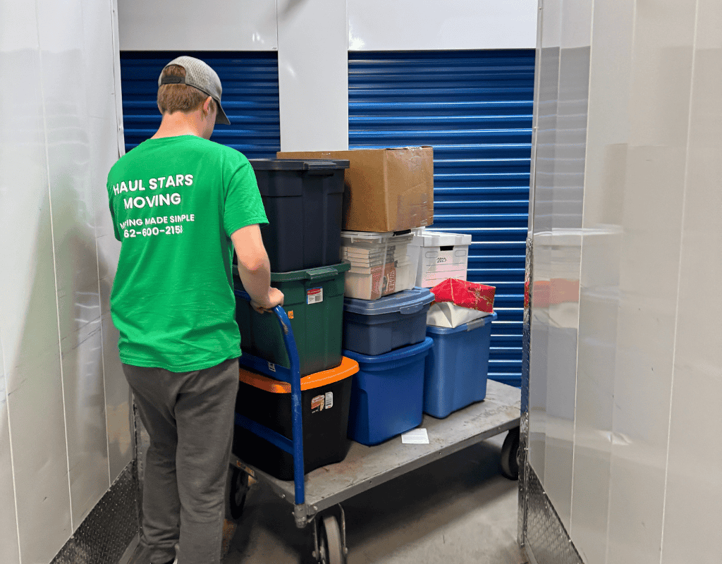 Haul Stars Moving employee pushing a cart loaded with plastic bins into a storage unit in Milwaukee