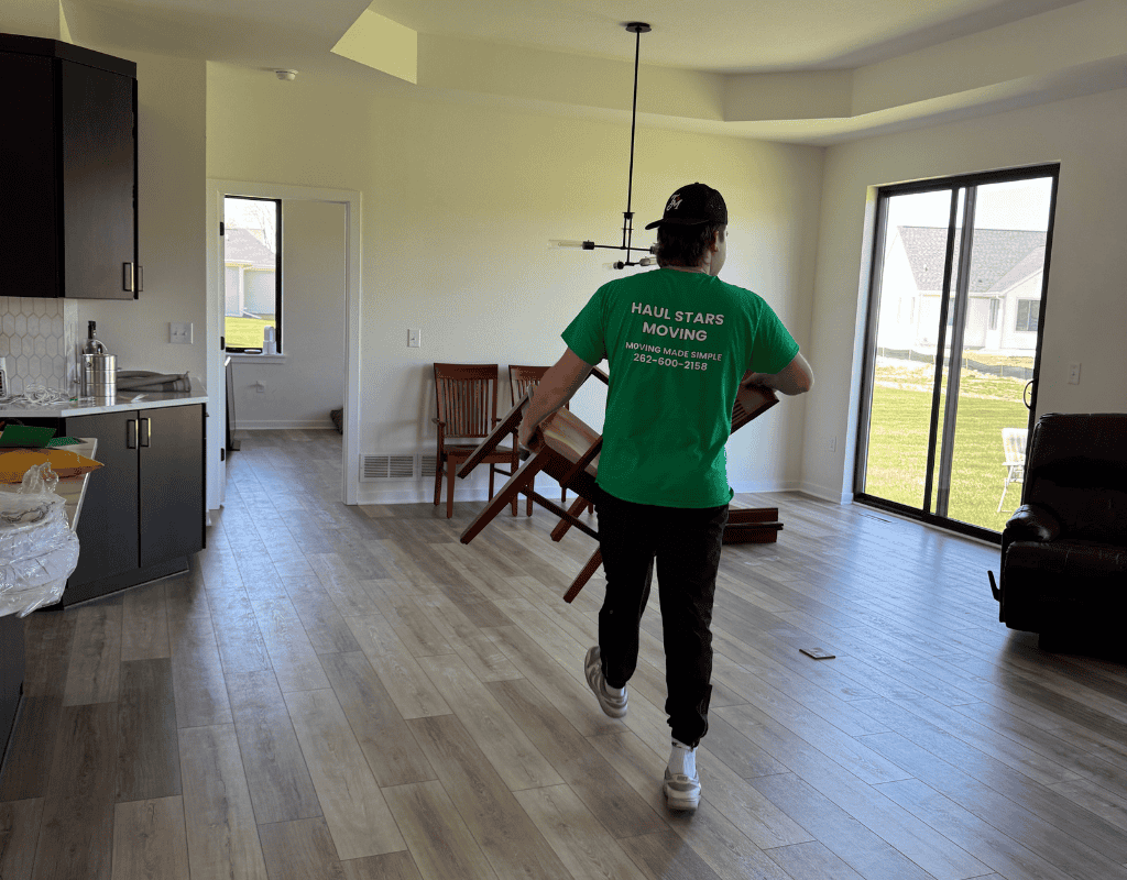 Haul Stars Moving team member carrying a dining chair through a doorway during a furniture pickup in Milwaukee
