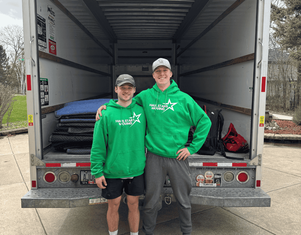 Two smiling Haul Stars Moving crew members standing inside an open moving truck in Milwaukee