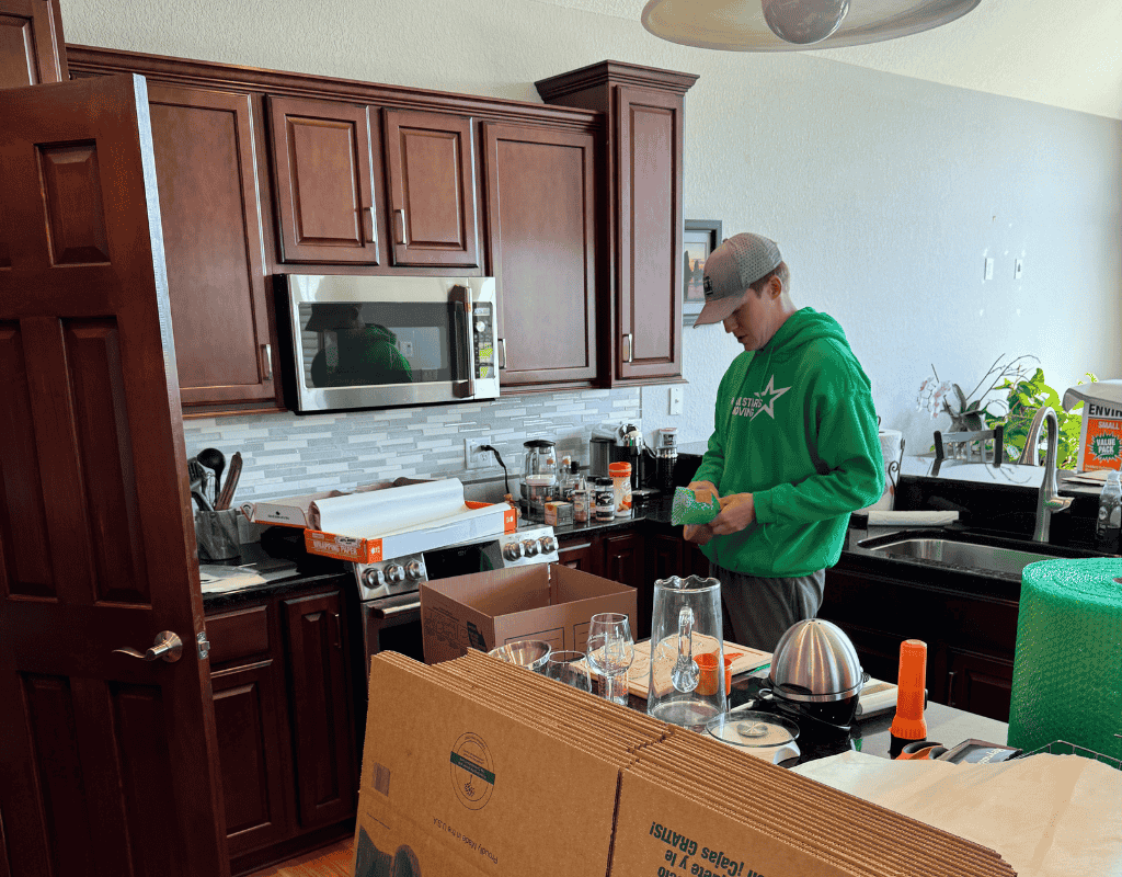 Mover wrapping kitchen items in bubble wrap inside a Milwaukee kitchen during a packing session
